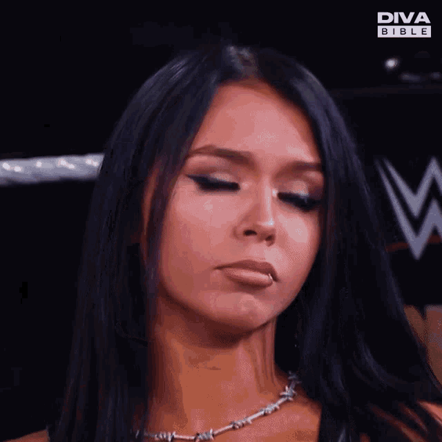 a woman is wearing a barbed wire necklace and a diva bible logo in the background