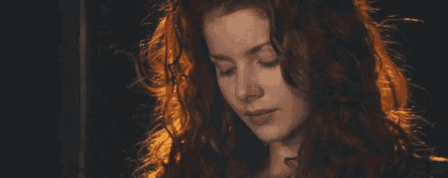 a close up of a woman with red hair looking down