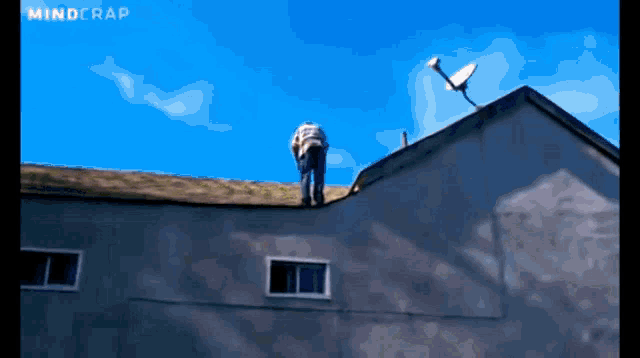 a man is standing on the roof of a building with a satellite dish on top of it