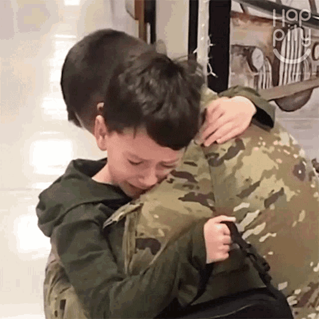 a young boy hugging a man in a military uniform