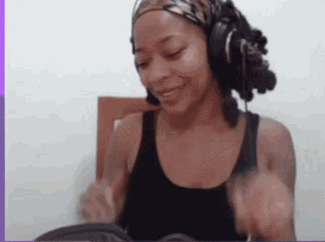 a woman wearing headphones and a headband is smiling while sitting on a chair .