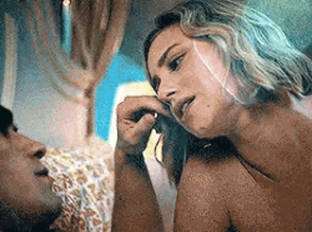 a man and a woman are laying on a bed . the woman is touching the man 's nose .