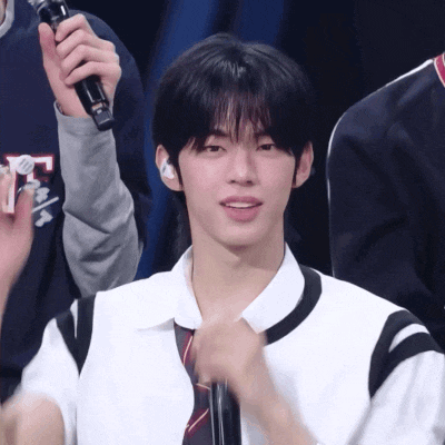 a young man in a white shirt and tie is holding a microphone in his hand
