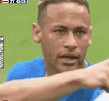 a man in a blue shirt is making a funny face while standing on a field .