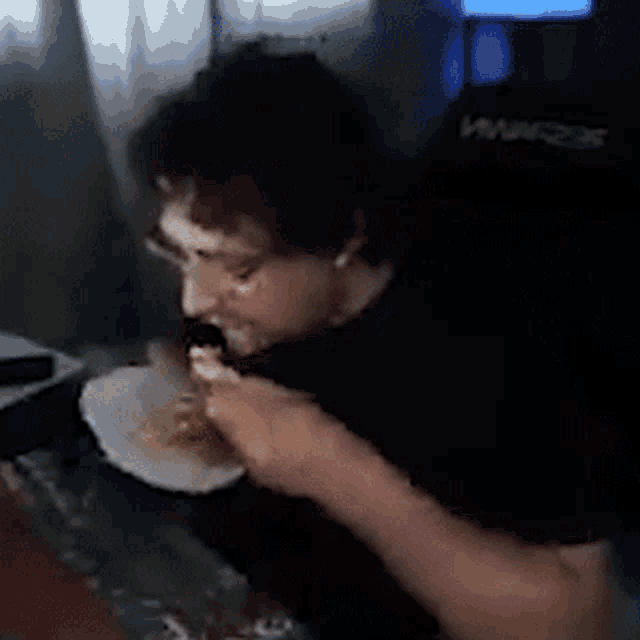 a man is sitting at a table eating a sandwich .