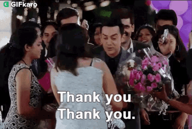 a group of people are standing around a man holding a bouquet of flowers and a woman holding flowers .