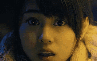 a close up of a woman 's face with a surprised look on her face and a scarf around her neck .