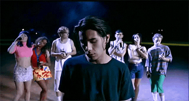 a man in a blue shirt is standing in front of a crowd of people .