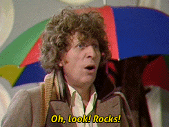 a man with curly hair holding an umbrella says oh look rocks