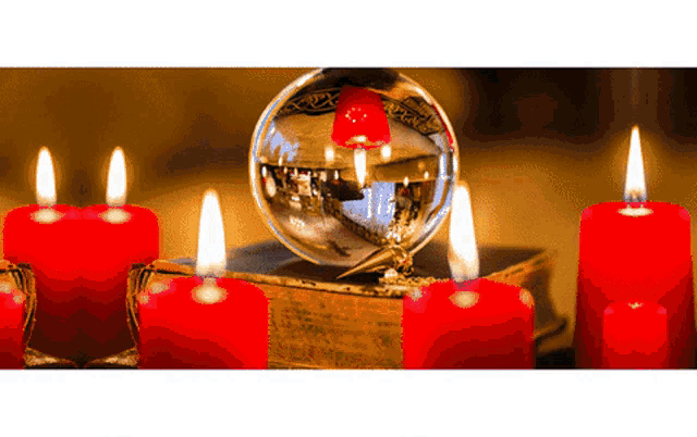 a glass ball sitting on top of a book with red candles around it