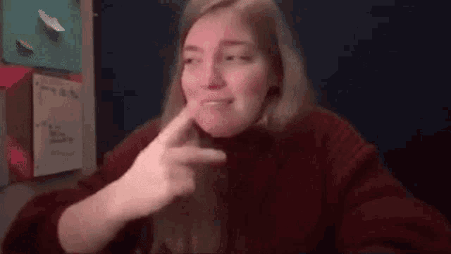 a woman in a red sweater is making a funny face while sitting at a table .