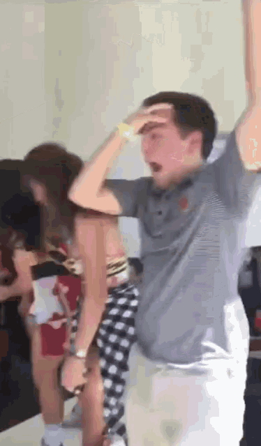 a group of people are dancing in a room with a man wearing a grey polo shirt