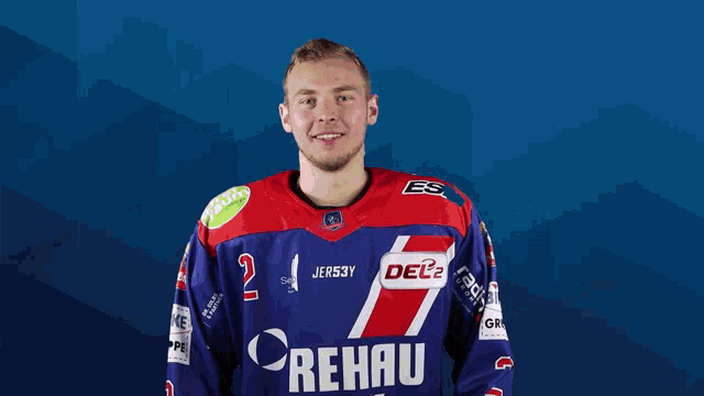 a man wearing a blue and red rehau jersey poses for a picture