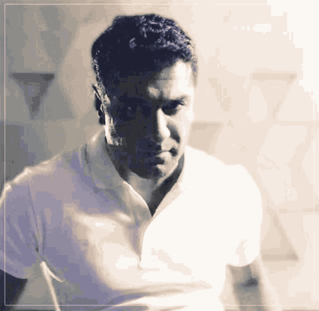 a man in a white shirt is standing in front of a wall with triangles