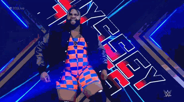 a man in a colorful outfit is standing in front of a sign that says wwe .
