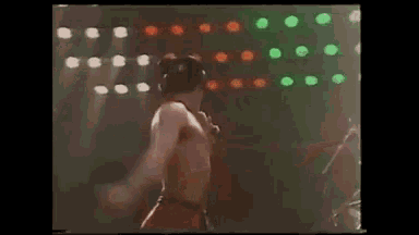 a man without a shirt is singing into a microphone on a stage .