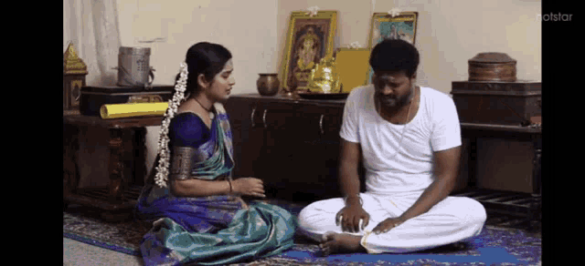 a man and a woman are sitting on the floor in a living room