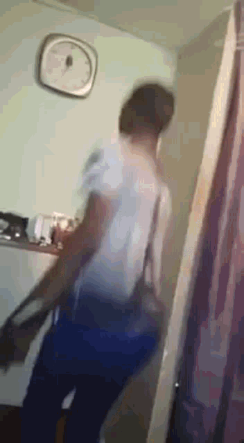a man is standing in a room with a clock on the wall .