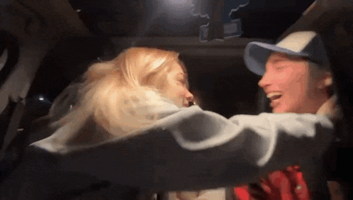 a man and a woman are hugging each other in the back seat of a car .