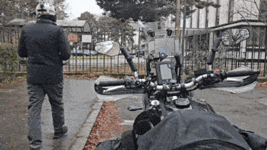 a man wearing a helmet stands in front of a motorcycle parked in a parking lot