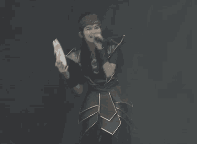 a woman in a costume is holding a piece of paper and a microphone .