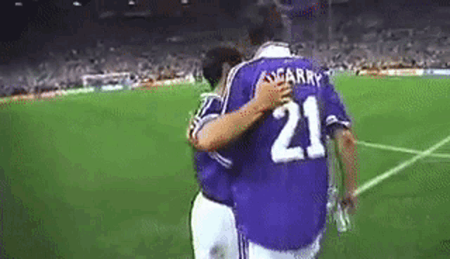two soccer players are hugging each other on the field .