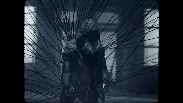a person in a hooded jacket is surrounded by a bunch of black wires
