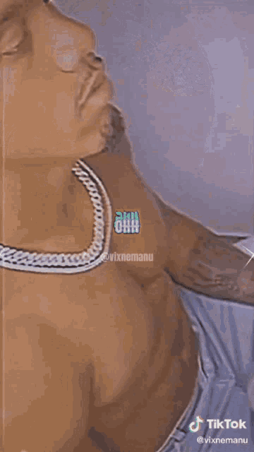 a shirtless man wearing a chain around his neck is laying on a bed .