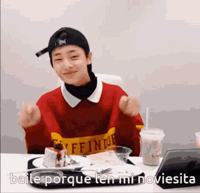 a boy is sitting at a table with a plate of food and a laptop and says baile porque len mi noviesita .