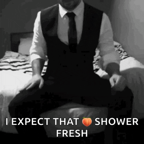 a man in a suit and tie is sitting on a bed and says `` i expect that shower fresh ''