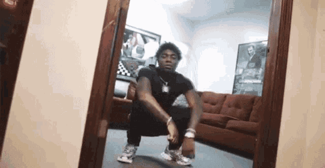 a young man is squatting in front of a mirror in a living room .