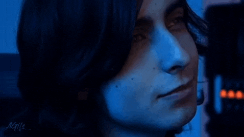 a close up of a man 's face with long hair in a blue light .