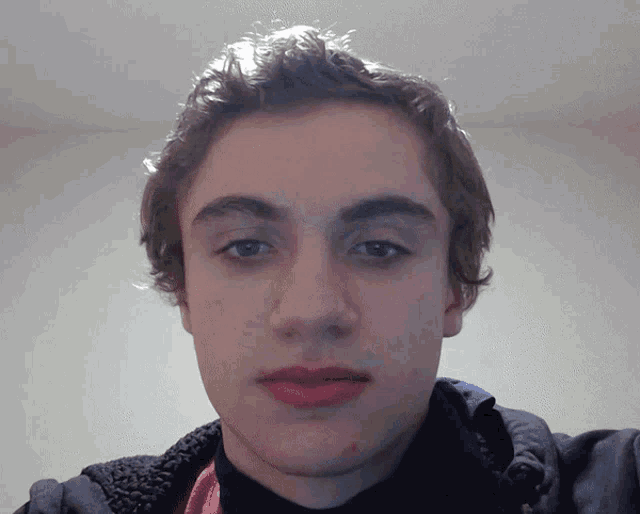 a young man with a scarf around his neck is taking a selfie