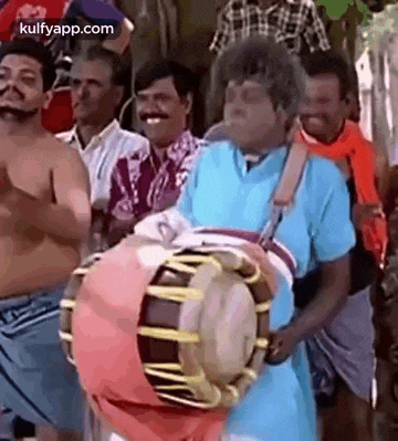 a man is playing a drum in front of a crowd of men .