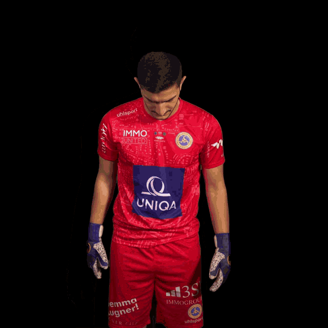 a man is wearing a red jersey with a blue patch that says uniqa