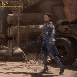 a woman in a blue armor stands in front of a jeep