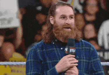 a man in a plaid shirt is holding a microphone with the letters nfm on it