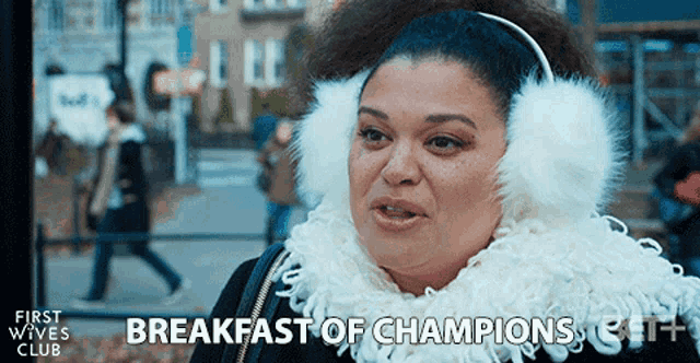 a woman wearing ear muffs and a scarf with the words breakfast of champions below her