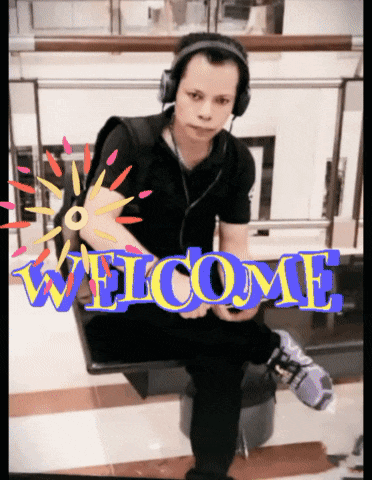 a man wearing headphones sits in front of a sign that says " welcome "