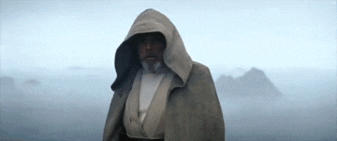 a man with a beard wearing a hooded cape is standing in the fog .