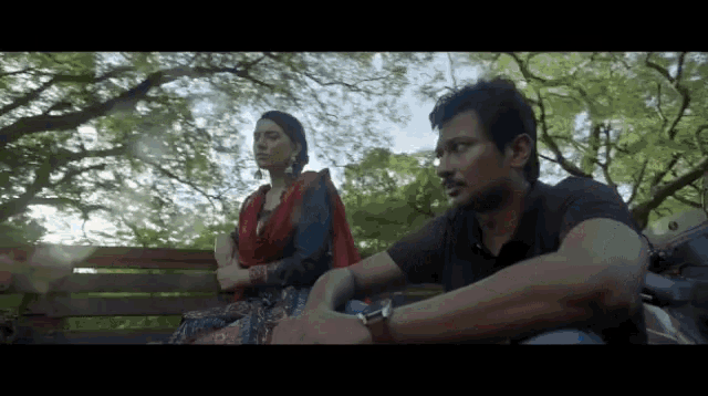 a man and a woman are sitting on a bench talking