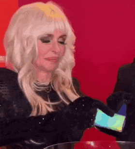 a woman with blonde hair is holding a cell phone in her hands .