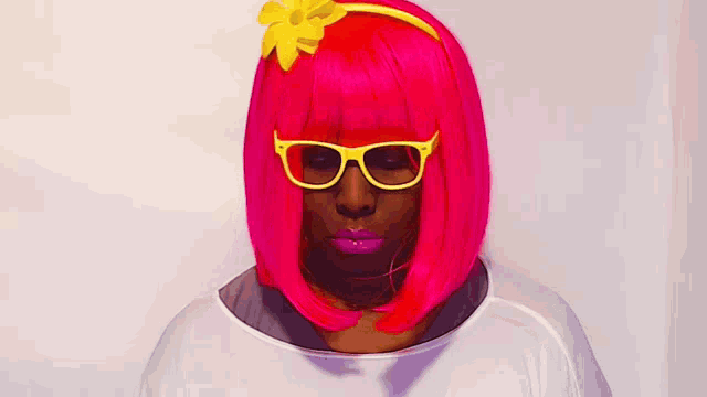 a woman wearing a bright pink wig and yellow glasses is smiling .