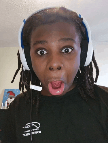 a person wearing headphones and a black shirt that says ' armour ' on it making a funny face