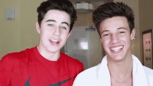 two young men are smiling for the camera and one has a red nike shirt on