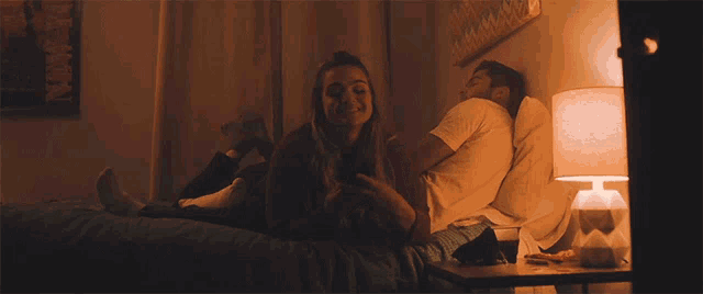 a man and woman laying on a bed with a lamp