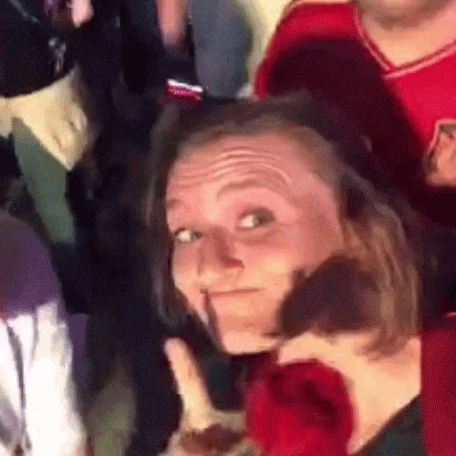 a woman is making a funny face while holding a rose in her mouth .