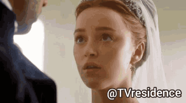 a woman in a wedding dress is looking at a man in a tuxedo .
