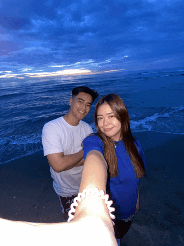 a man and a woman pose for a photo on the beach