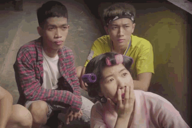 a woman with curlers on her hair is sitting with two men